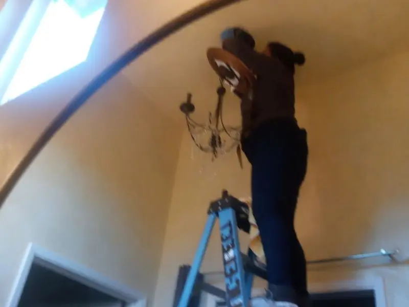 Electrician installing a chandelier in a Dilworth residence